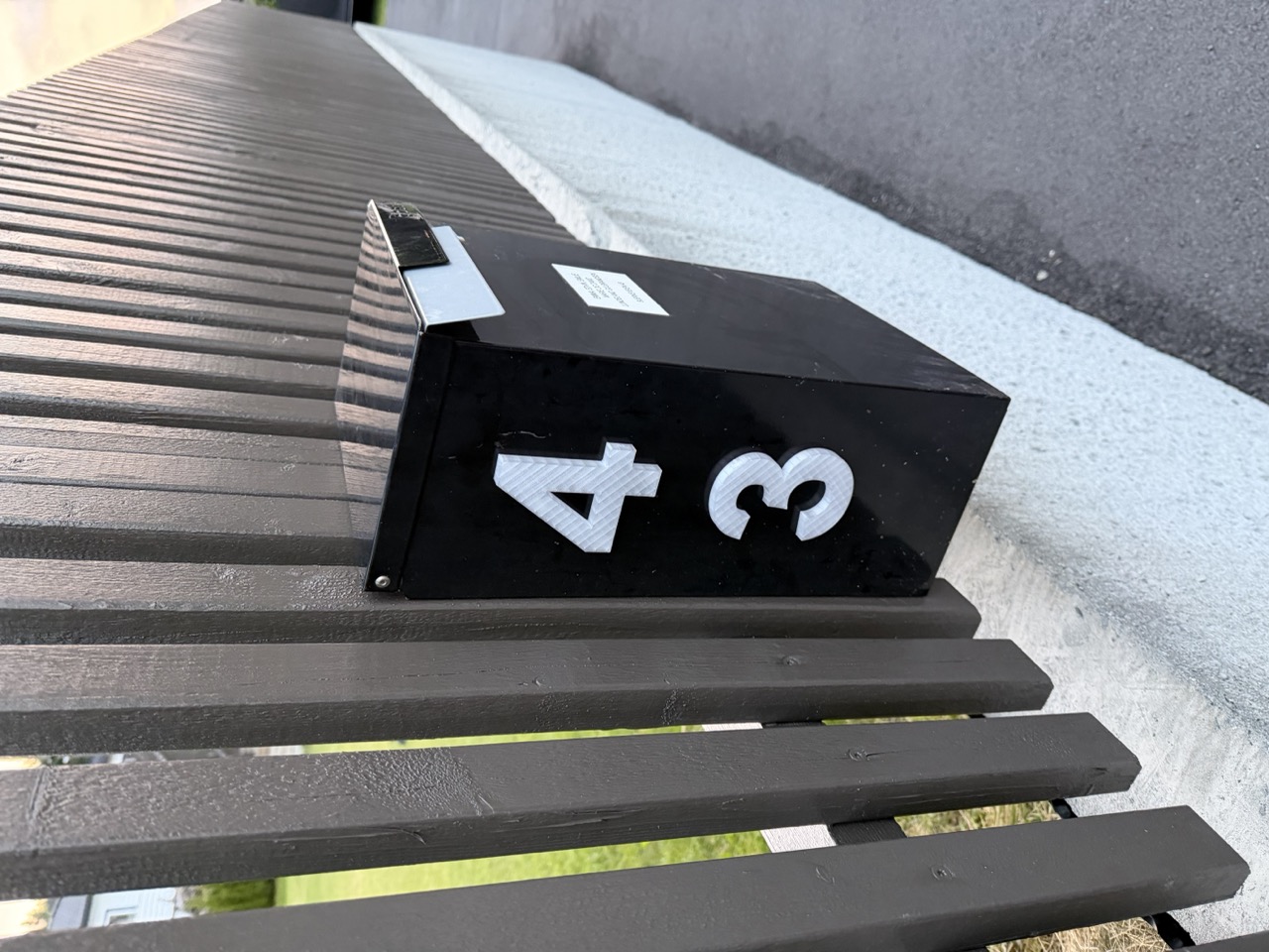 3D-printet husnummer 43 i hvitt på svart postkasse, synlig fra veien